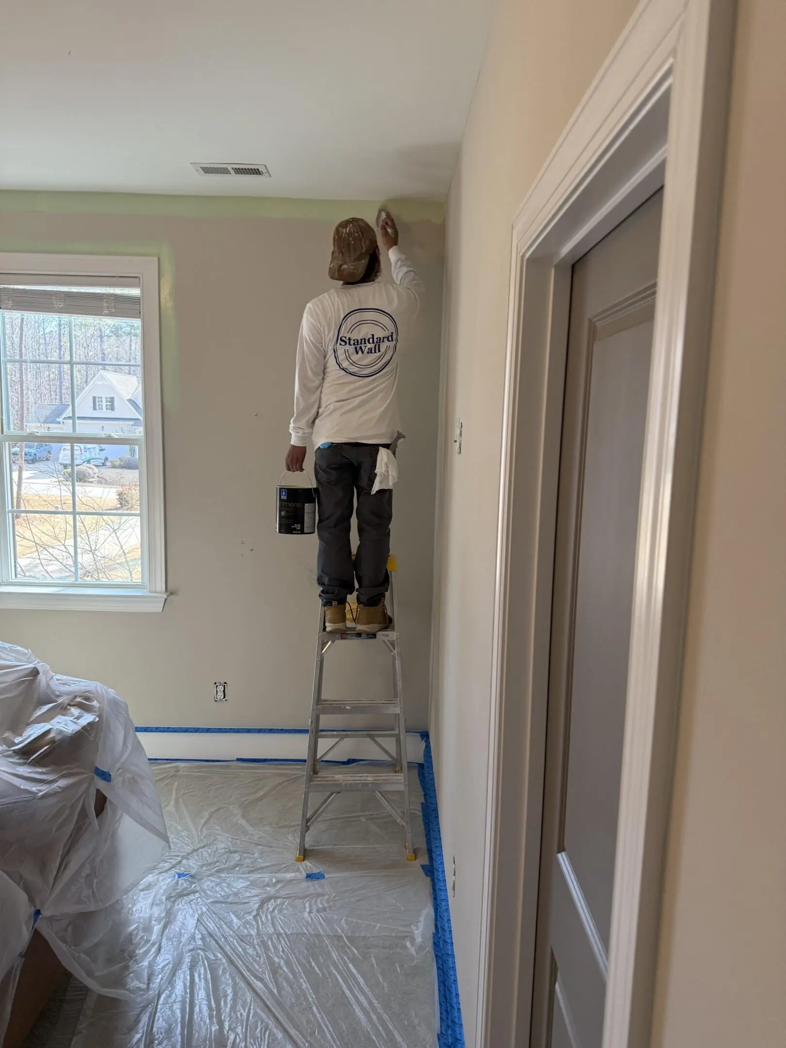 Painter on ladder painting interior wall