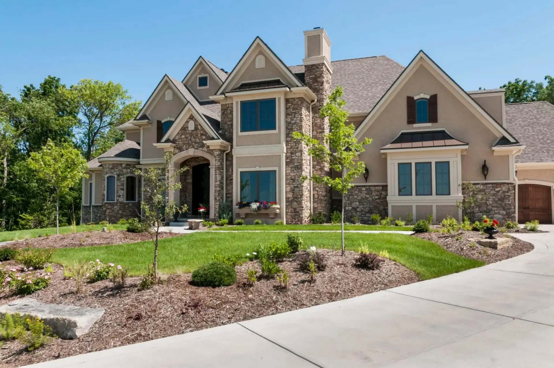Stone-and-stucco luxury house with manicured landscaping
