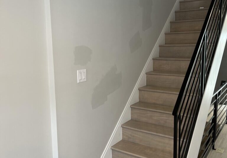 Modern wooden staircase with patched gray wall