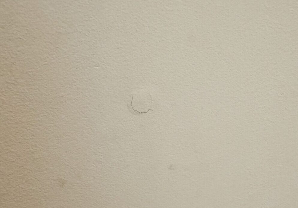 Off-white wall with small circular paint chip