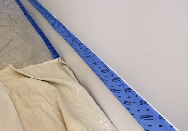 Blue painter's tape along baseboard with drop cloth